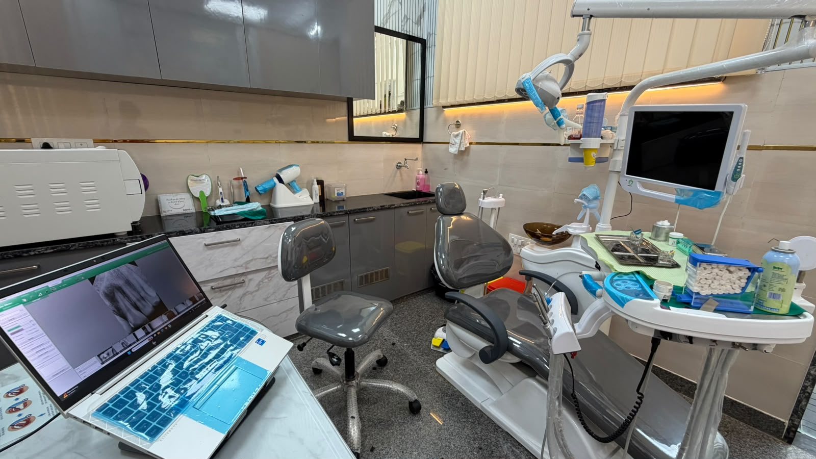 Treatment room at Dentinium Dental Studio with digital X-ray on the laptop, autoclave and dental chair